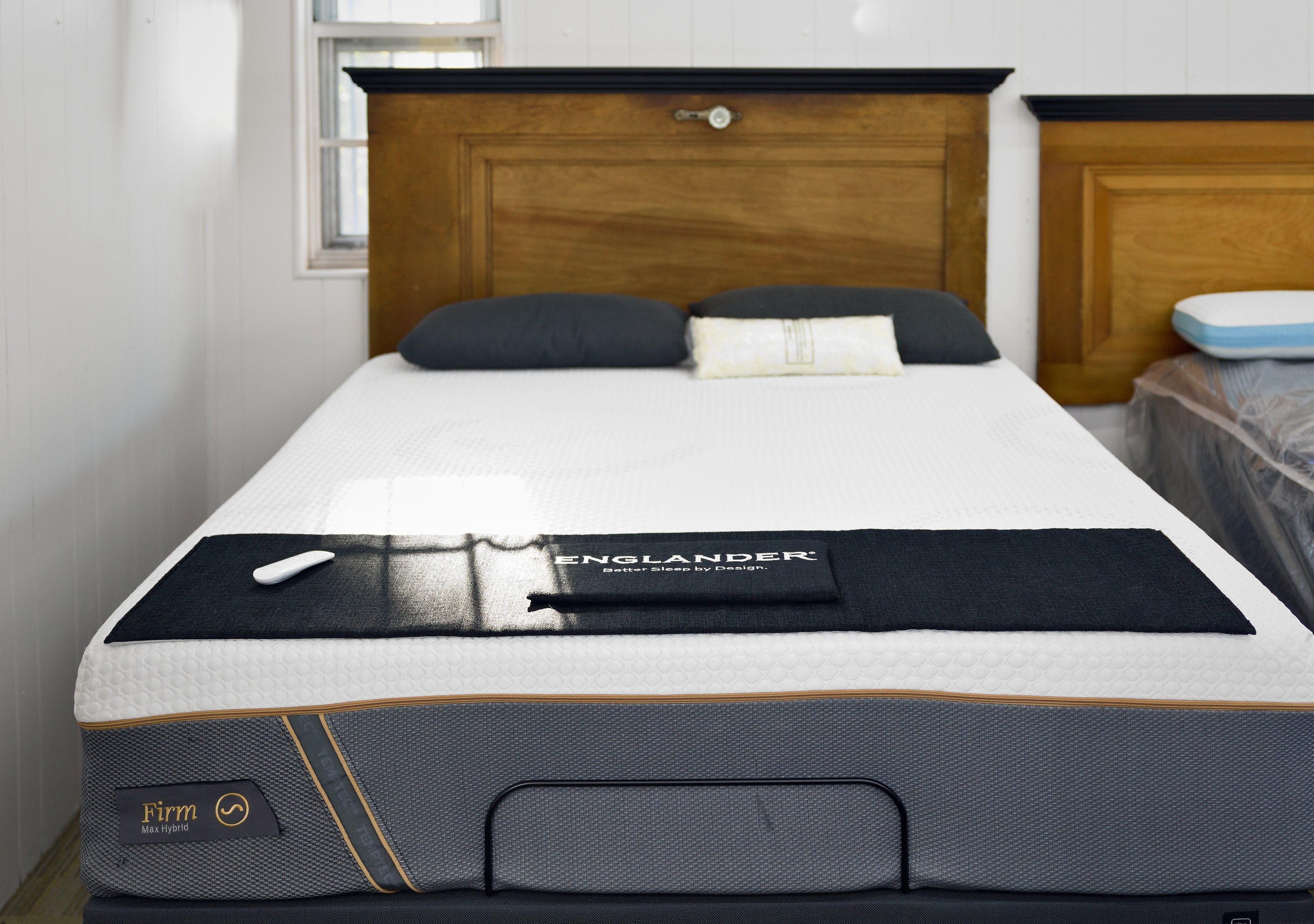 An Englander mattress on an adjustable base in the showroom, under a wood headboard