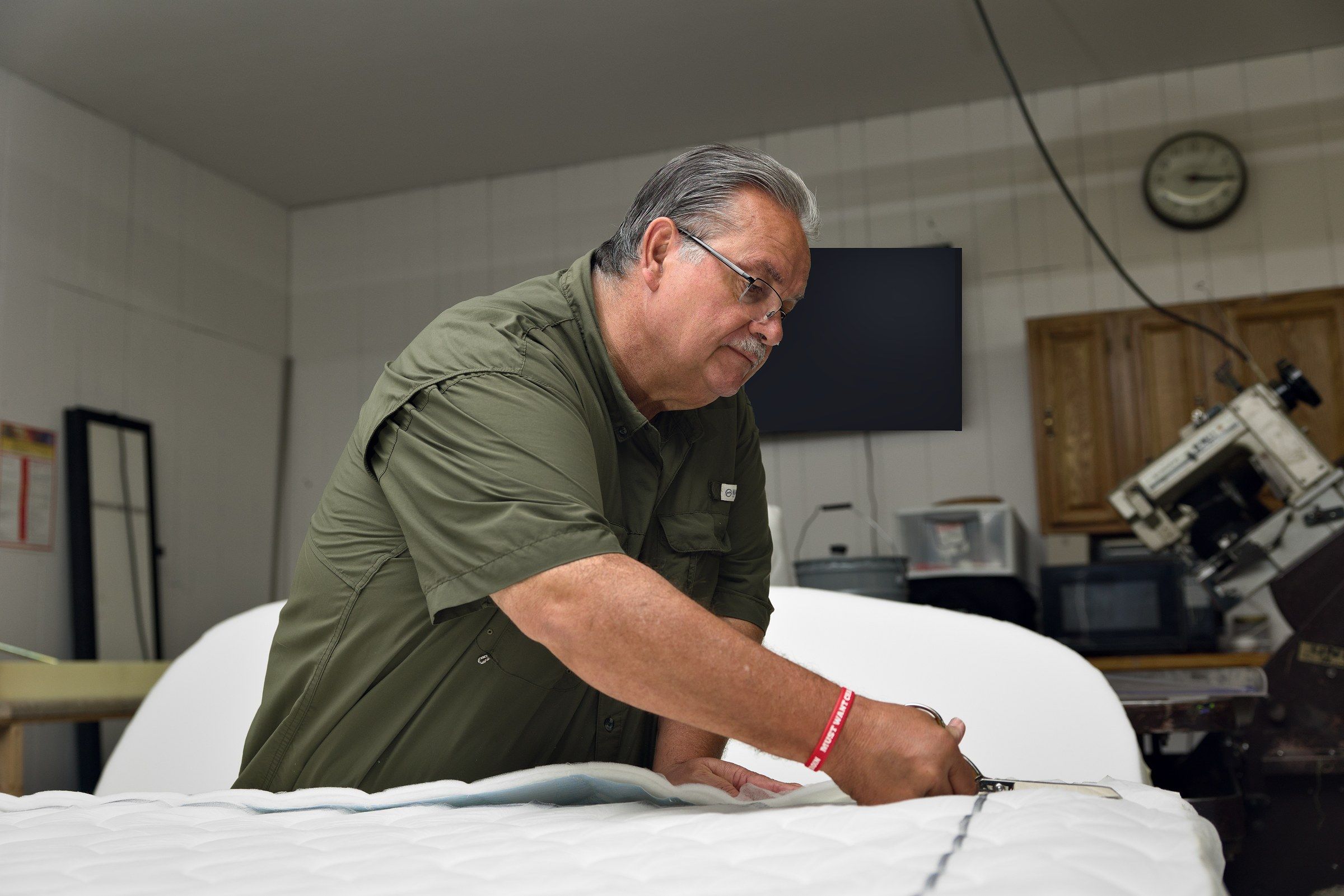 Clinton trimming the quilted border of a mattress in the shop